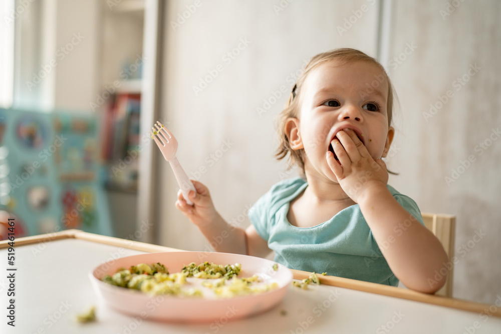 one girl small caucasian child one year old eat at the table at home one girl small caucasian child one year old eat at the table at home