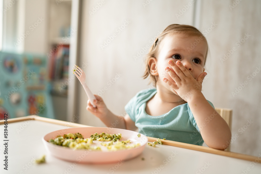 one girl small caucasian child one year old eat at the table at home one girl small caucasian child one year old eat at the table at home