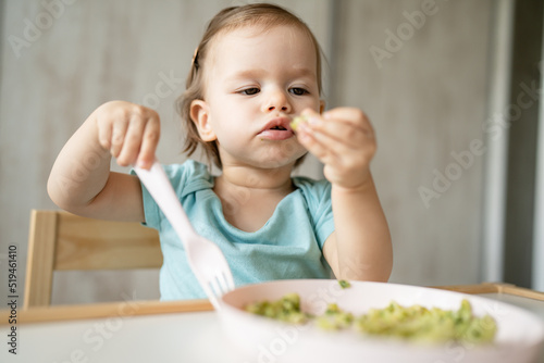 one girl small caucasian child one year old eat at the table at home