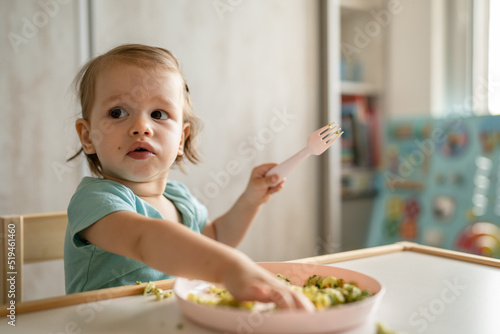 one girl small caucasian child one year old eat at the table at home