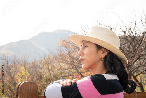 mujer sola con sombrero reposando en tranquera de madera photo