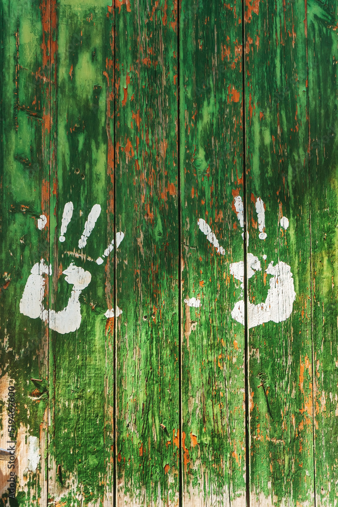 Human handprints on a green wall. White handprints on an old door
