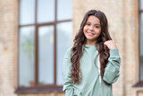 Happy teenage girl with long curly hair posing in casual style blurry outdoors, copy space