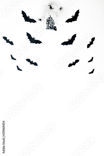  Black paper bats fly over a mystical castle with a cobweb and a black cat on a white background. Halloween concept and decorations. copy space