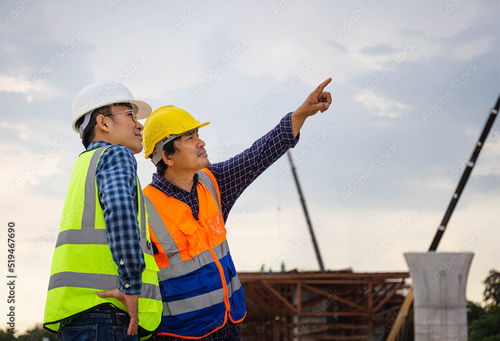 Engineer and foreman worker checking project at building site, Engineer and builders in hardhats in infrastructure construction site, Teamwork concepts Engineer and foreman worker checking project at building site, Engineer and builders in hardhats in infrastructure construction site, Teamwork concepts