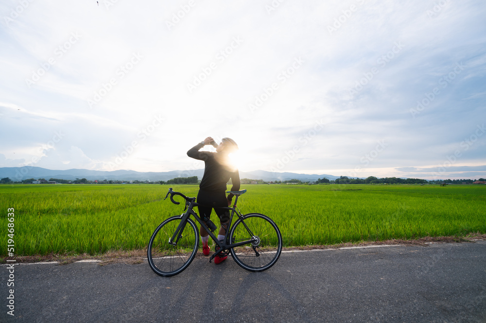 Obraz premium Cyclist is drinking water and look at the beautiful view while having a break