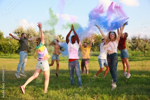 Happy friends having fun with colorful powder dyes outdoors. Holi festival celebration