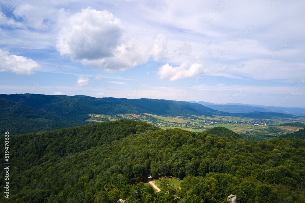Aerial view of high hills with dark pine forest trees at autumn bright day. Amazing scenery of wild mountain woodland