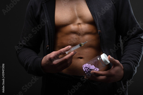 Muscular man with a syringe in his hand. User of anabolic steroids for strength training photo