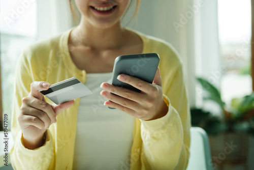 Asian woman hands holding credit card and using cell, smart phone.