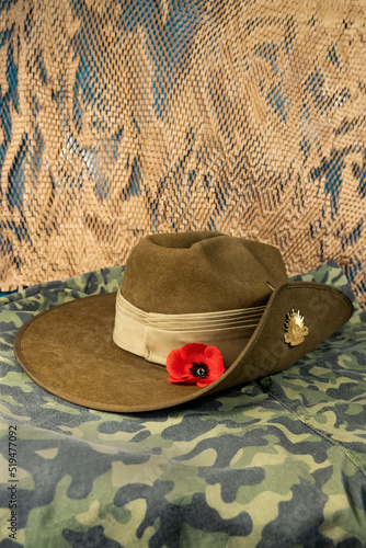 Australian army slouch hat or diggers hat with badge and a red poppy on a background of camoflage pattern.
