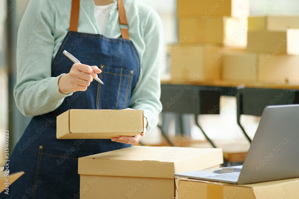 Online small business owner writing address on parcel box.