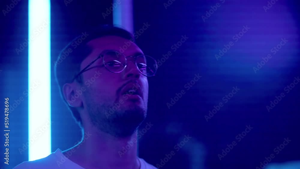 Close-up of a young man dancing in a nightclub, smoking an electronic cigarette under a neon light. Night club Close-up of a young man dancing in a nightclub, smoking an electronic cigarette under a neon light. Night club