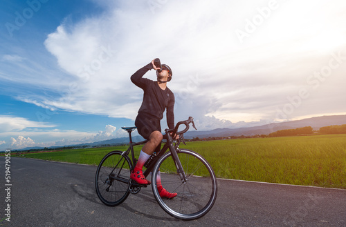 Fototapeta Naklejka Na Ścianę i Meble -  Cyclist man is drinking water from the sports bottle