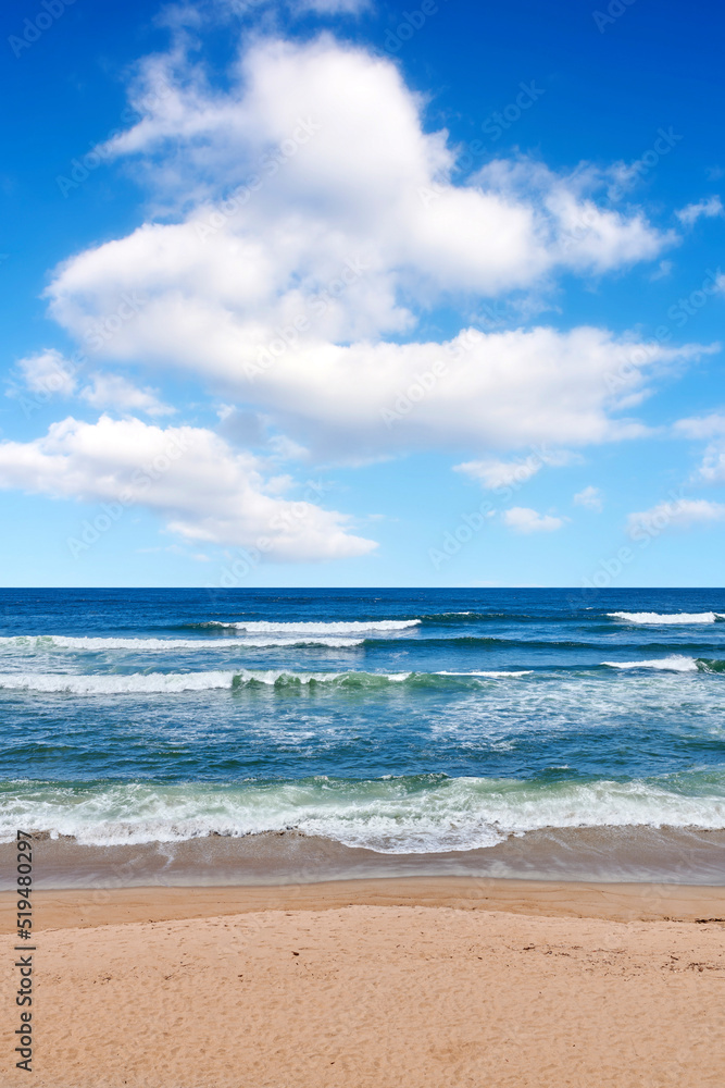 Beautiful, calm and quiet view of the beach, ocean and seashore against a cloudy blue sky on a summer day. Peaceful and remote ocean and sea with waves rolling into the shore in a natural environment