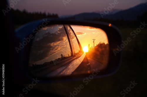 Beautiful sunset in sideview car mirror on mountain road © Vedrana