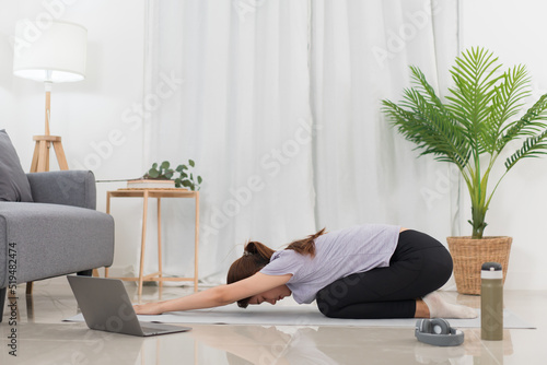 Yoga exercise concept, Asian woman doing yoga with lying in child pose in class online at home photo