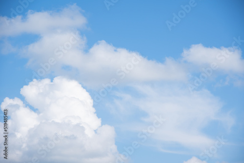 Blue sky background with white fluffy cumulus clouds. Panorama of white fluffy clouds in the blue sky. Beautiful vast blue sky with amazing scattered cumulus clouds.