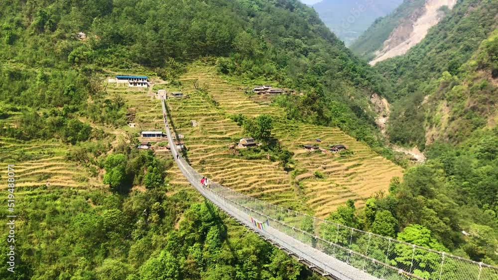 Hikers walking over the big suspension bridge in Annapurna region, Nepal Hikers walking over the big suspension bridge in Annapurna region, Nepal