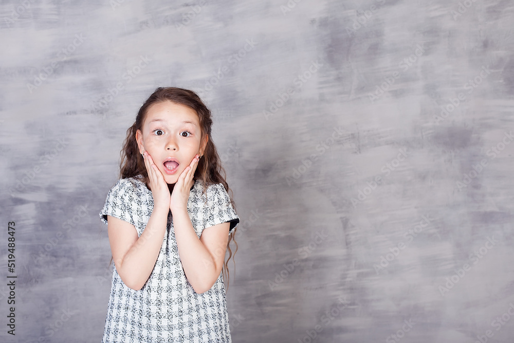 A beautiful European girl is surprised. Portrait of a 7-year-old child on a white background. Children's emotions, gestures A beautiful European girl is surprised. Portrait of a 7-year-old child on a white background. Children's emotions, gestures
