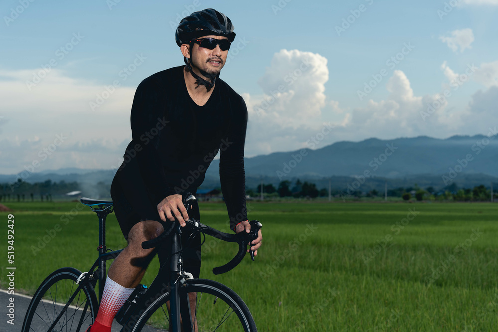 Fototapeta premium Front view of professional cyclist in cycling training suit against green nature blur background Healthy fitness and lifestyle concepts