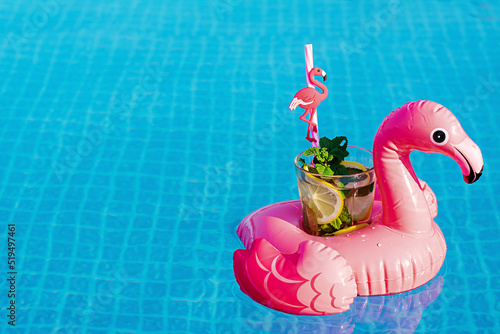 Fresh coctail mojito on inflatable pink flamingo toy at swimming pool. Vacation concept.