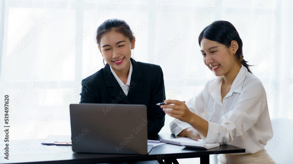 Two professional Asian business women discuss work using a laptop computer to work in the office. Two professional Asian business women discuss work using a laptop computer to work in the office.