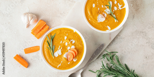 Bowls of tasty carrot cream soup on light background, top view photo