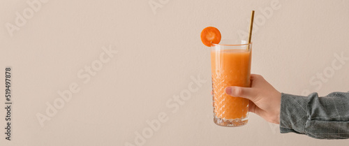 Female hand with glass of healthy carrot smoothie on light background with space for text