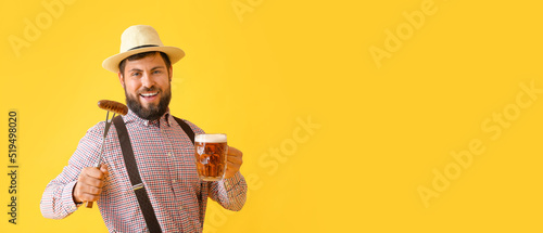 Handsome man in traditional German clothes, with beer and sausage on yellow background with space for text