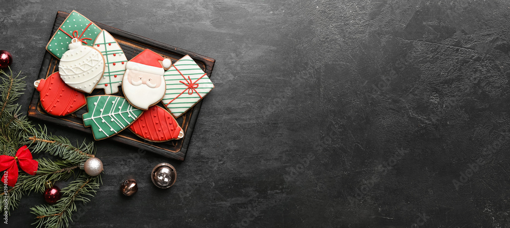 Board with delicious Christmas cookies and decor on dark background with space for text
