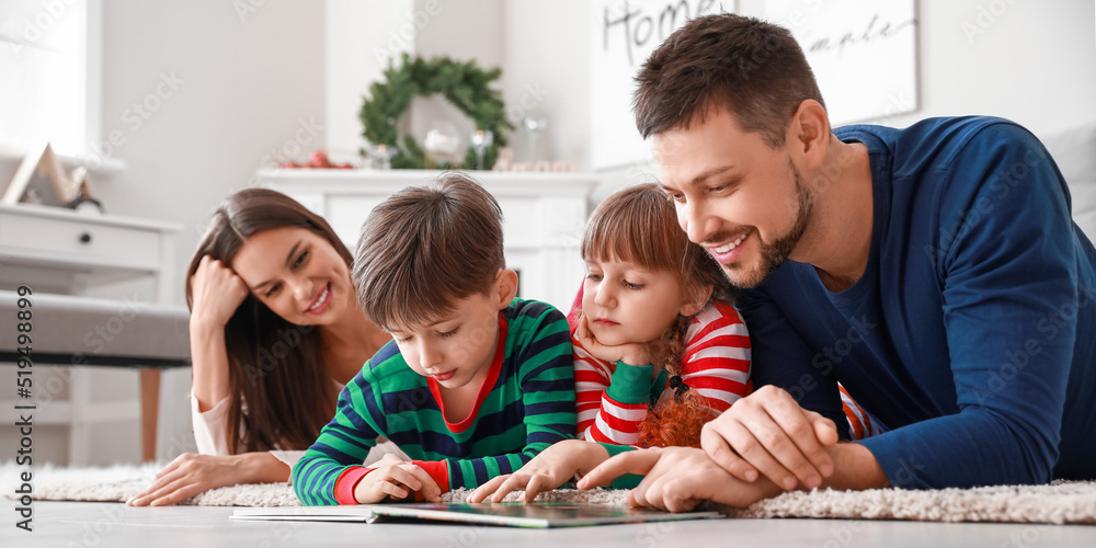Happy family reading book at home on Christmas eve Happy family reading book at home on Christmas eve