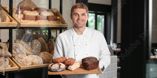 Male baker holding board wi...