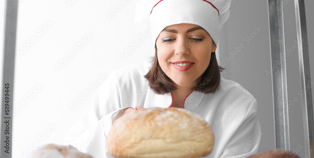 Female baker with fresh bread in kitchen Female baker with fresh bread in kitchen
