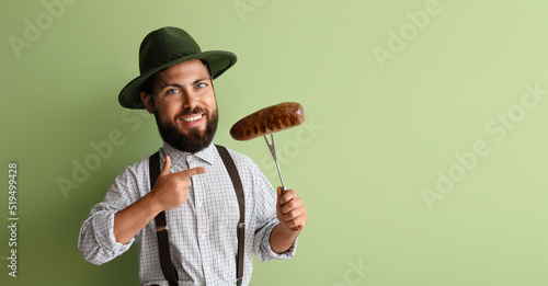 Funny man with big head in traditional German clothes and with sausage on green background. Octoberfest celebration