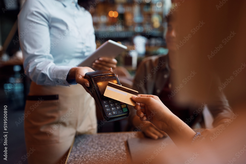 Close up of woman paying contactless with credit card in cafe. Close up of woman paying contactless with credit card in cafe.