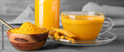 Cup of healthy turmeric drink on grey wooden background