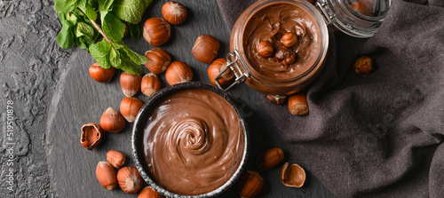 Cuadro en lienzo Bowl and jar with tasty chocolate paste and hazelnuts on dark background, top vi