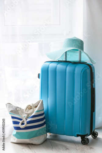 Blue suitcase  straw hat and bag in light room