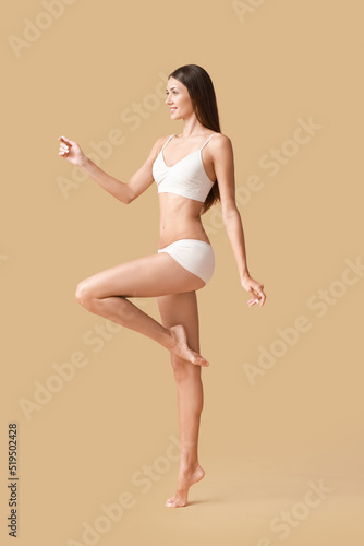 Young tanned woman in underwear on beige background © Pixel-Shot