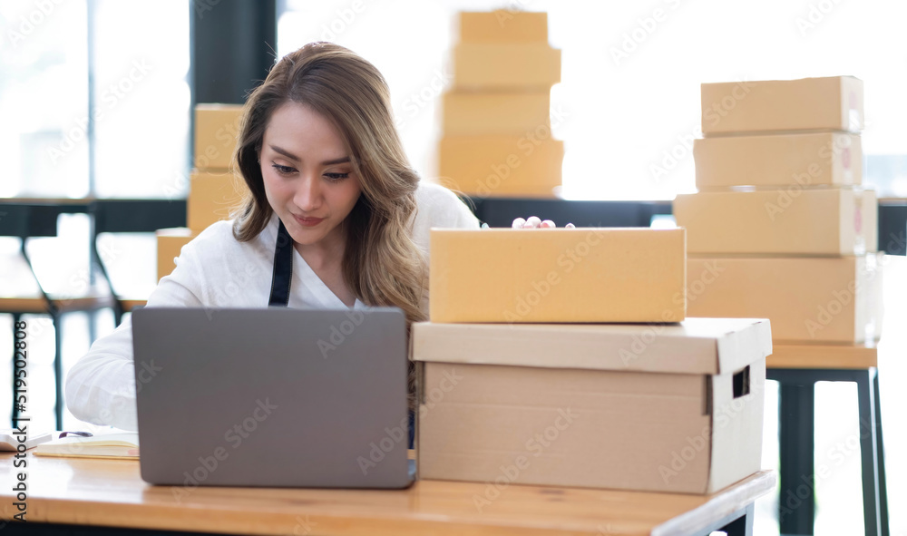Portrait of Asian young woman SME working with a box at home the workplace.start-up small business owner, small business entrepreneur SME or freelance business online and delivery concept. Portrait of Asian young woman SME working with a box at home the workplace.start-up small business owner, small business entrepreneur SME or freelance business online and delivery concept.