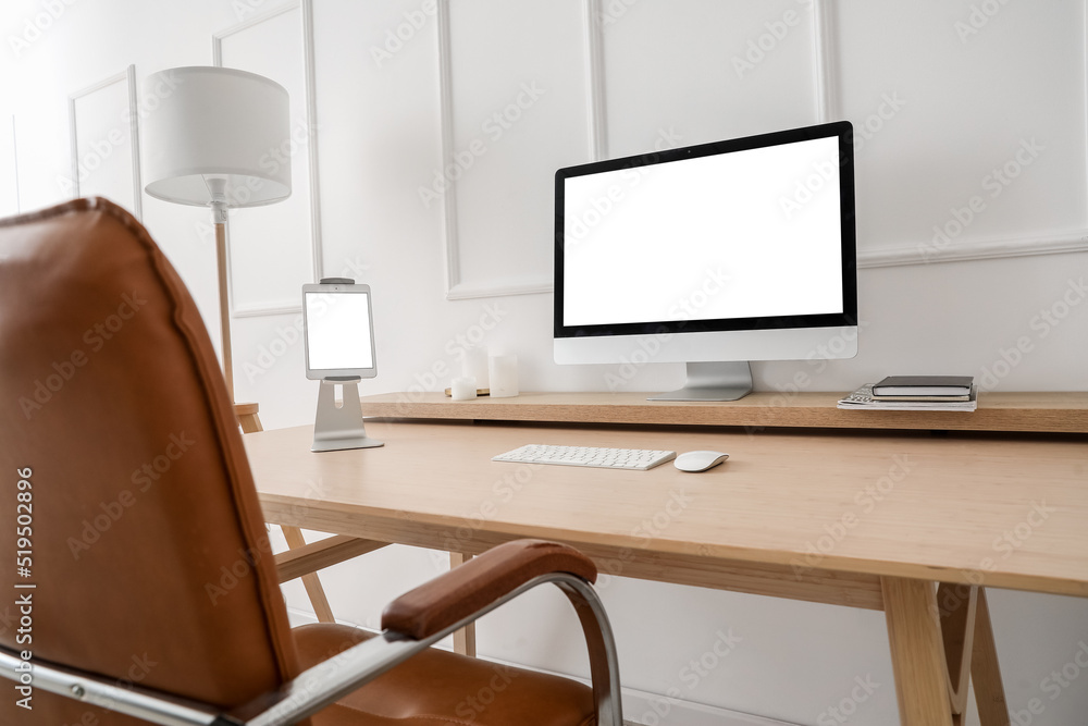 Modern workplace with computer and tablet near light wall Modern workplace with computer and tablet near light wall