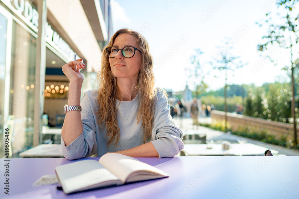 Casual woman sitting at table and taking notes in notebook .on the cafe terrace Casual woman sitting at table and taking notes in notebook .on the cafe terrace