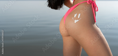 Фотография sun cream on a woman buttocks over the sea background. banner