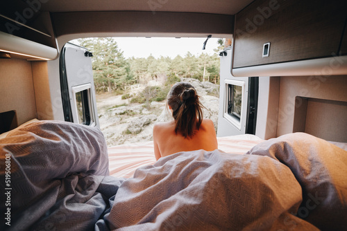 Topless woman lying on bed in RV from behind