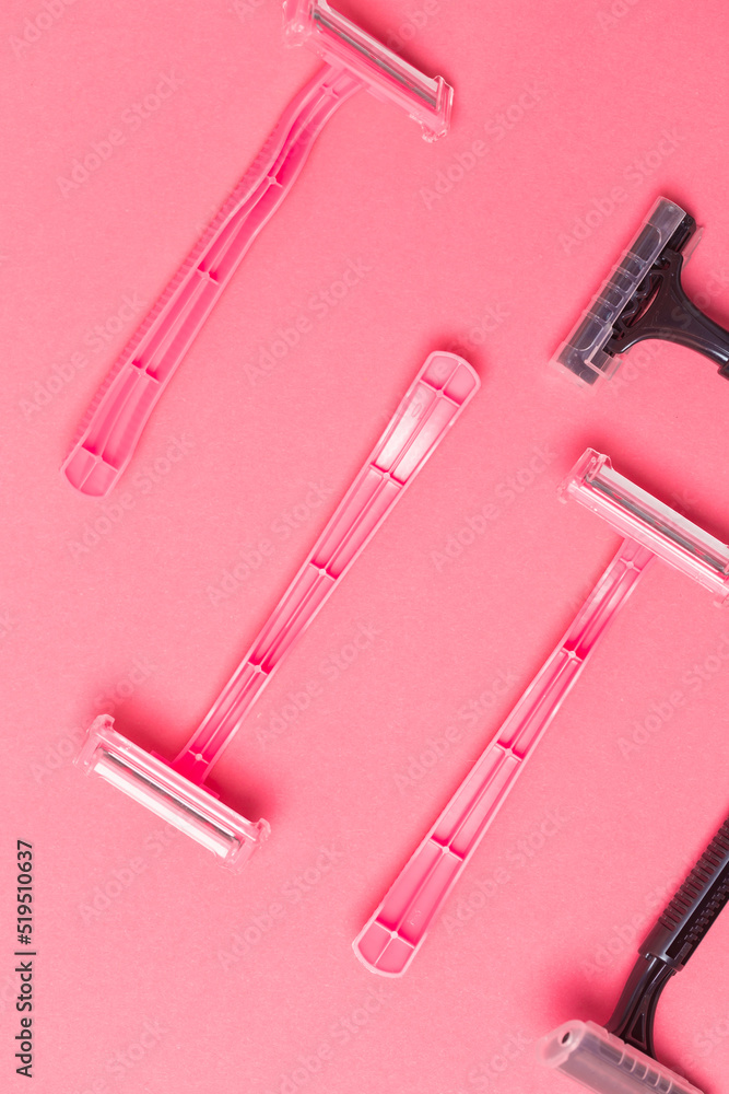 Shaving Concepts. Flat-Lay Image of Various Women's Colorful Pink and Black Disposable Razors Shavers Placed in Different Directions On Pink Coral Background. Shaving Concepts. Flat-Lay Image of Various Women's Colorful Pink and Black Disposable Razors Shavers Placed in Different Directions On Pink Coral Background.