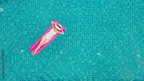 Top view of young asian woman in swimsuit on the pink air mattress in the swimming pool.