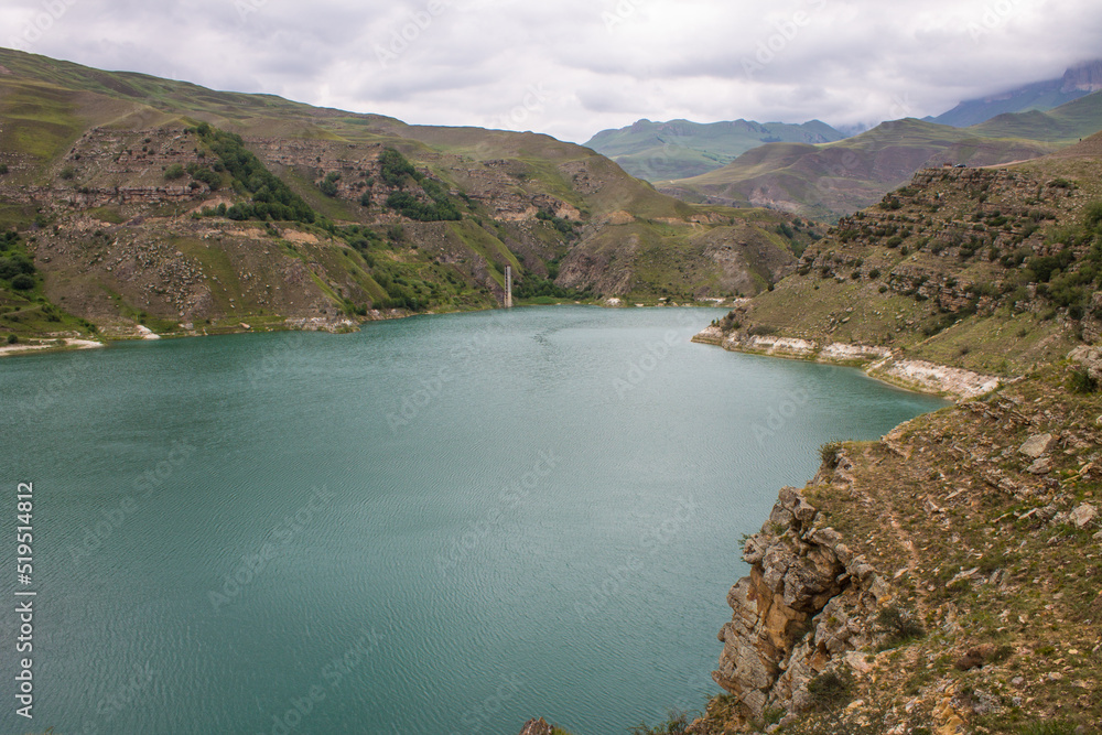 Lake Gizhgit turquoise high in the mountains with hilly shores and a cloudy summer day