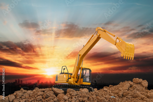 Excavator is digging in the construction site ,on a sunset background .