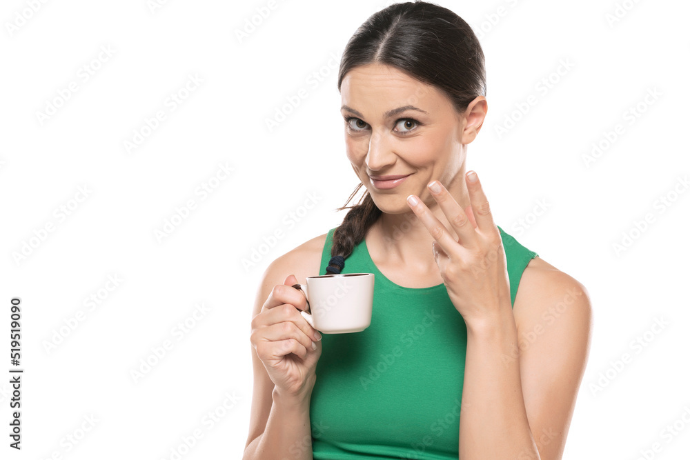 A young smiling woman gossips with a cup of coffee in her hand on a white background A young smiling woman gossips with a cup of coffee in her hand on a white background